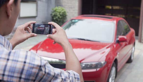 Autó tulajdonos fotót készít az autójáról a hirdetéshez.