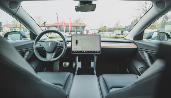 Egy Tesla elektromos autó beltere. A kormányon Tesla logó látható, a középső kijelzőn pedig a navigáció van megnyitva.