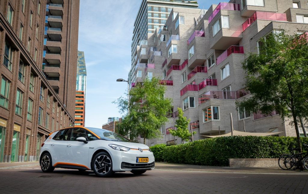 Fehér, elektromos Volkswagen ID.3, mögötte lakóépületekkel.