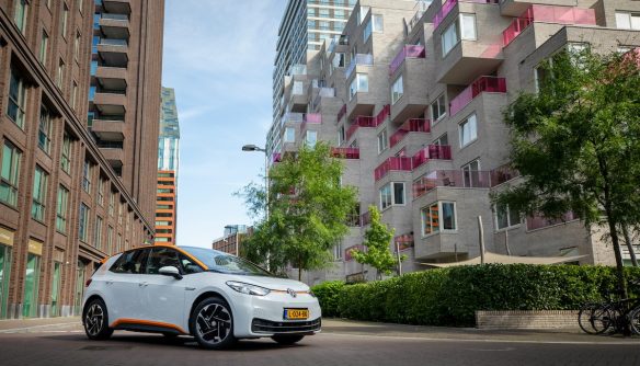 Fehér, elektromos Volkswagen ID.3, mögötte lakóépületekkel.