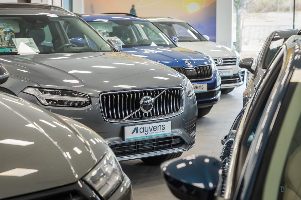 Eladó autók az Ayvens mobilitási szolgáltató kínálatában. A kép fókuszában egy szürke Volvo orra látható, rajta egy Ayvens logóval ellátott rendszámmal.