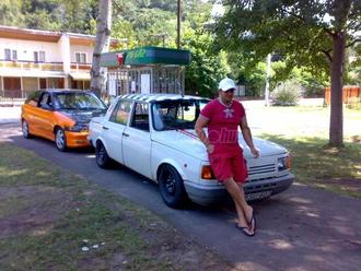 A meghirdetett autót kitakarja a nekitámaszkodó alak, mögötte másik jármű és épületek láthatóak.