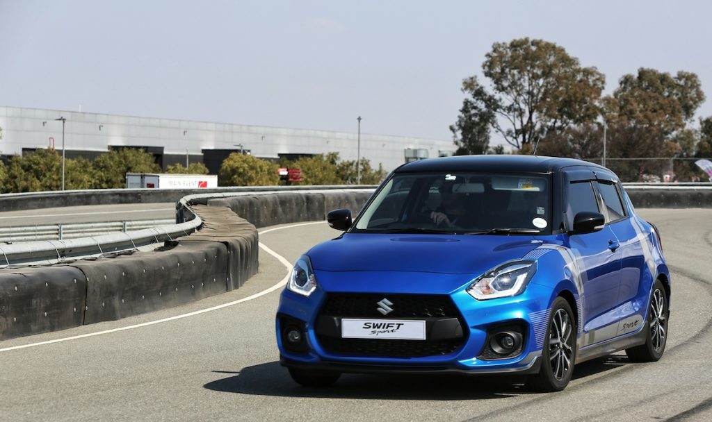 Kék Suzuki Swift egy kanyarodó úton.