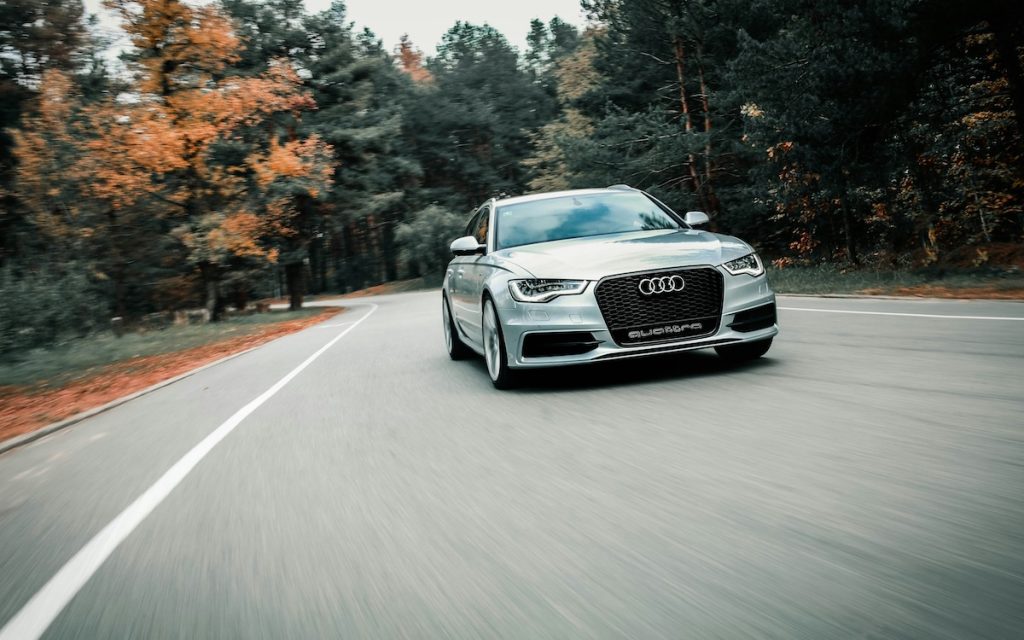 Szürke Audi hasít az úton, mögötte fák sárguló falevelekkel.