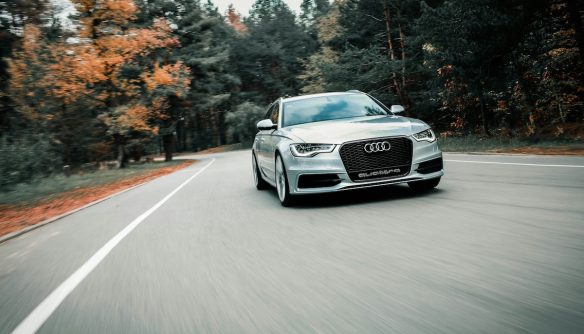 Szürke Audi hasít az úton, mögötte fák sárguló falevelekkel.