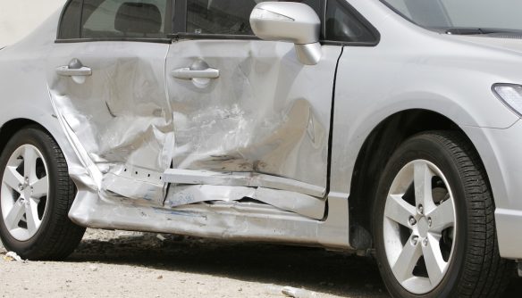 Balesetben sérült autó. Szürke szedán oldalütközés után, összetört ajtókkal.