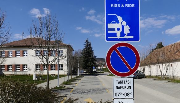 "Puszi és haladj" közlekedési tábla egy iskola mellett. A pár helyen már használt K+R táblát az új KRESZ tervezete is hivatalosan bevezeti.