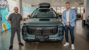 A Használtautó.hu GT videó borítóképe. Középen egy Jaecoo autó látható, amitől balra Lőcsei Dániel, jobbra pedig Izsó Péter áll.