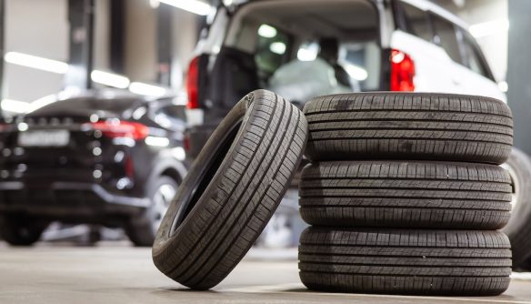 Egy garnitúra gumiabroncs, a háttérben egy használt autóval.