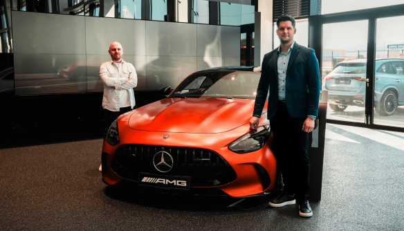 Lőcsei Dániel és Varga Gábor a Mercedes-Benz Miskolc vadonatúj márkakereskedésében, egy narancssárga Mercedes mellett.