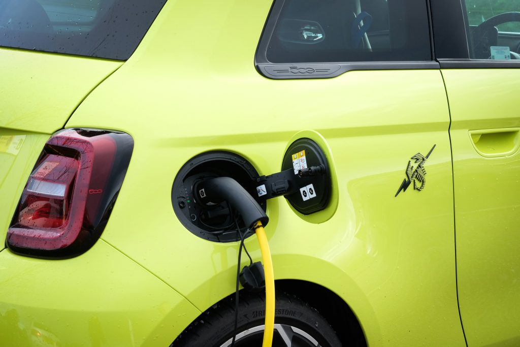 A képen egy sárga elektromos autó látható töltés közben.