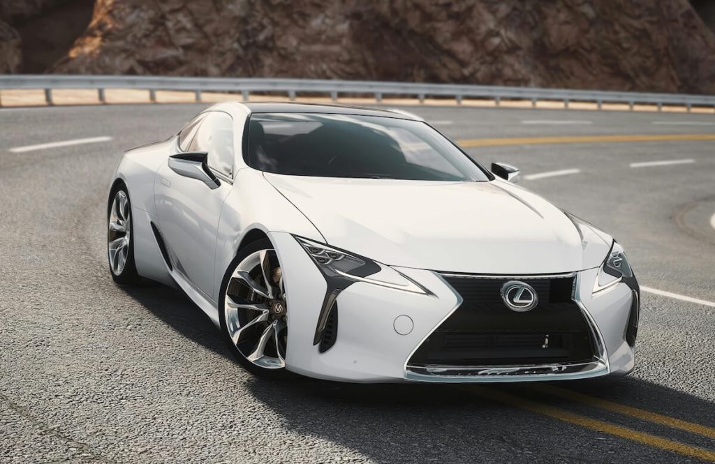Fehér Lexus LC 500 áll egy kanyarodó autópályán, mögötte sziklákkal.