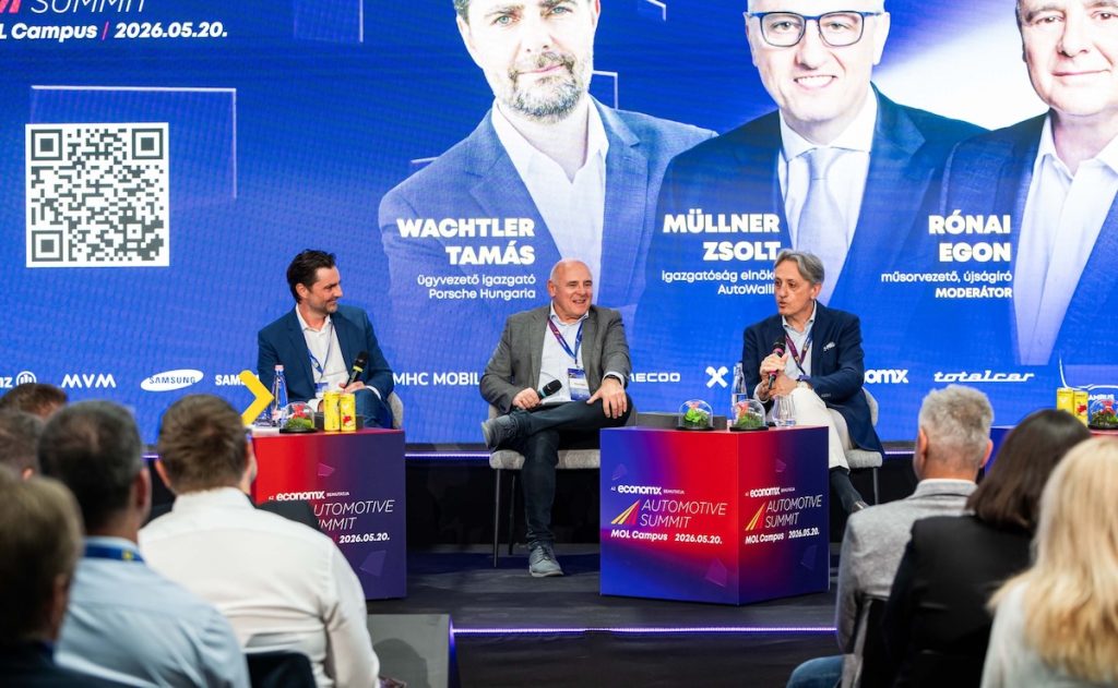 Az Automotive Summit 2026 színpada. Balra Wachtler Tamás (Porsche Hungária), középen Rónai Egon műsorvezető, jobbra Müllner Zsolt (AutoWallis) az európai autóipar kihívásairól beszélgetnek.