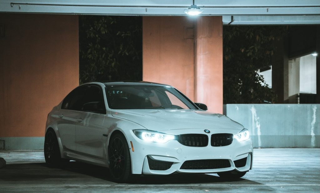 Fehér 3-as BMW a parkolóban, sötétedés után.