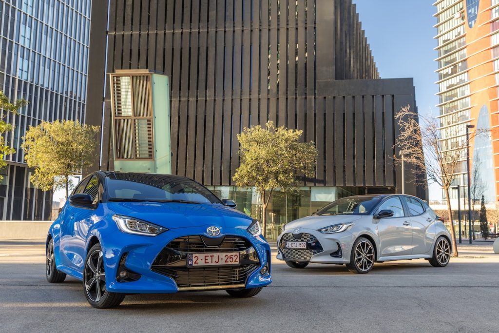 Egy kék és egy szürke 2024-es Toyota Yaris modern épületek előtt