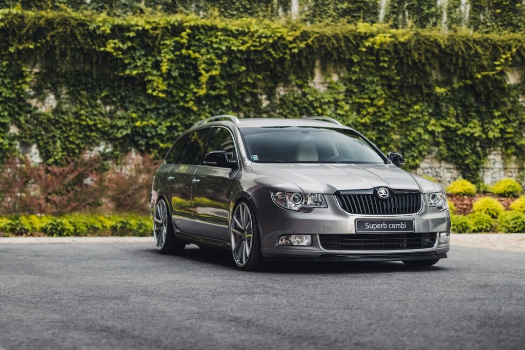 Egy szürke Skoda Superb parkol borostyánnal benőtt fal előtt. A kép a sleeper autó ajánlónk illusztrációja.