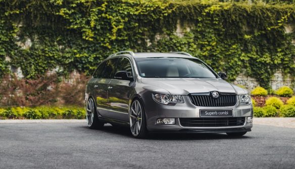 Egy szürke Skoda Superb parkol borostyánnal benőtt fal előtt. A kép a sleeper autó ajánlónk illusztrációja.