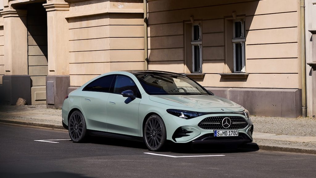 Szürke Mercedes-Benz CLA parkol az út szélén egy világos épület mellett.