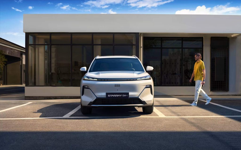 Egy Geely Starray EM-i modell elölnézetből, parkolóban. Jobbról a sofőr közelít az autóhoz. Kép forrása: https://www.geely.hu/