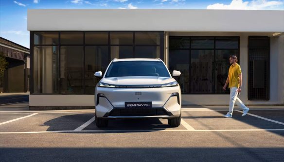 Egy Geely Starray EM-i modell elölnézetből, parkolóban. Jobbról a sofőr közelít az autóhoz. Kép forrása: https://www.geely.hu/